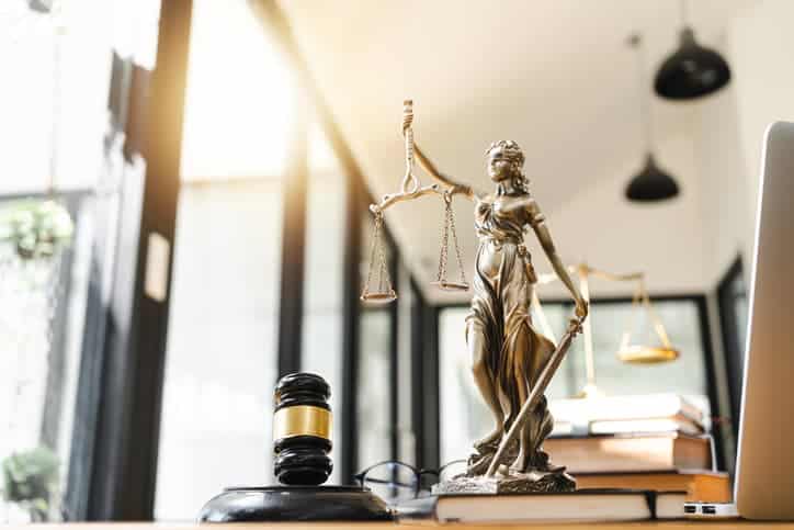 Estatua De La Justicia (Temis) Con Balanza En Escritorio De Oficina De Abogados, Mazo De Juez Y Libros De Fondo.
