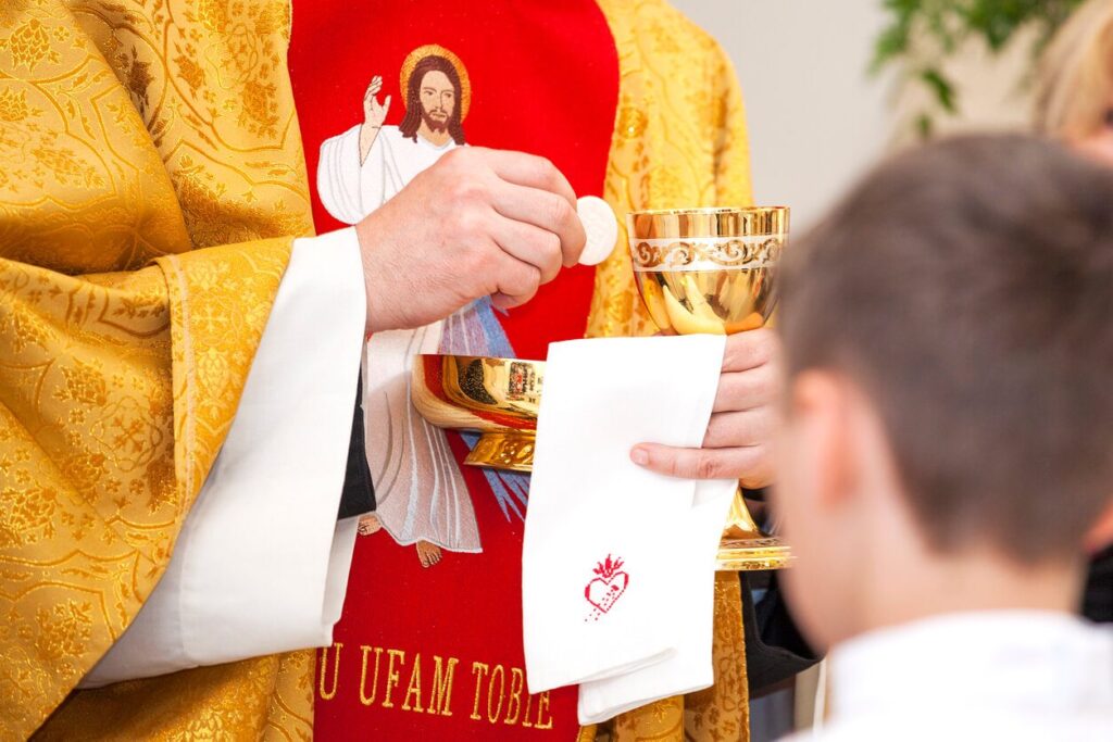 priest giving child communion