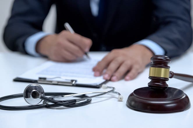 Judge signing arrest warrant for medical error, banging gavel near stethoscope