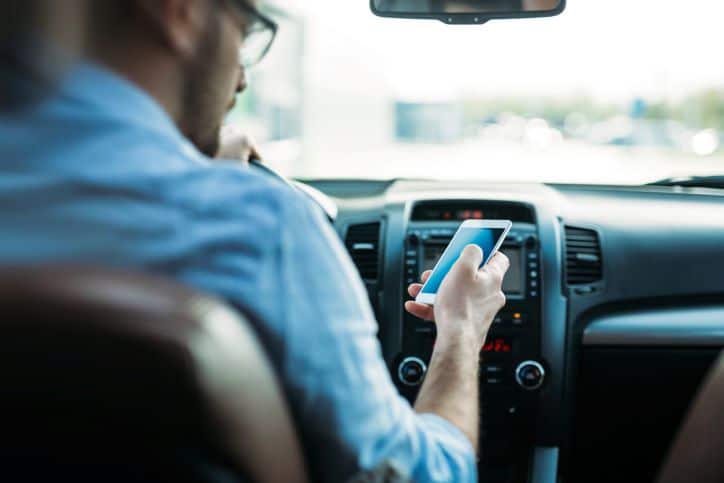 man driving while using his phone in his right hand