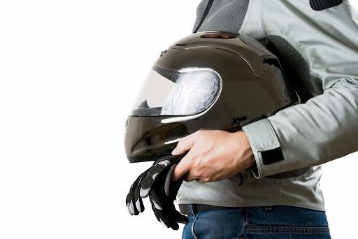 adult holding motorcycle helmet and gloves