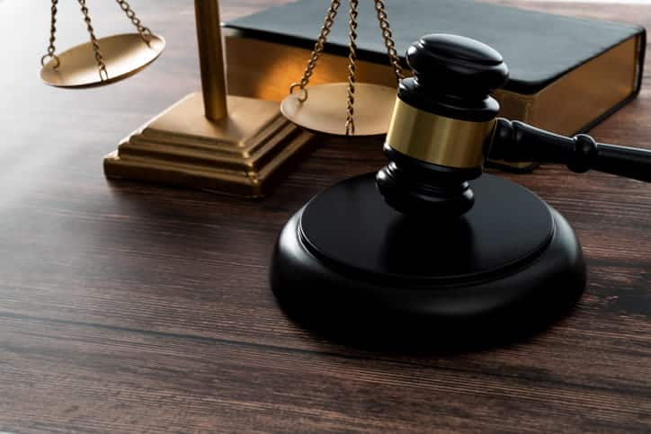 A gavel next to the scales of justice and a law book. 