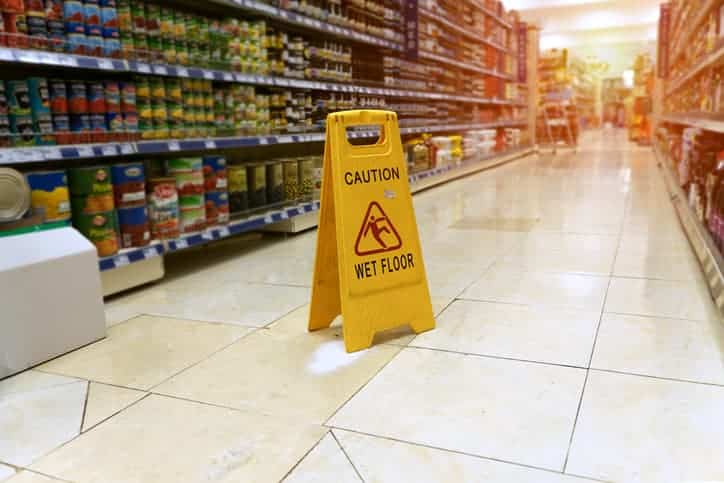 Caution wet floor sign in grocery store aisle 