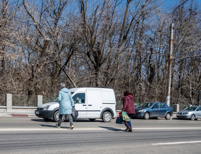 Pedestrians jaywalking in street with cars