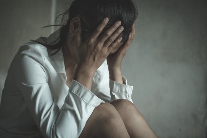 woman sitting with hands on her head in distress or pain