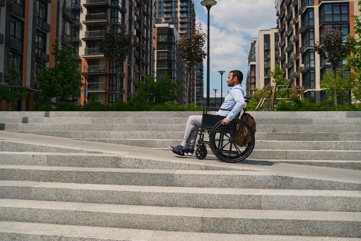 man in wheelchair going up ramp near stairs