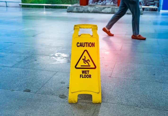 Hotel Slip And Fall Settlements In 2023 1 Yellow Caution Sign Warning Of A Wet Floor In An Indoor Public Space.