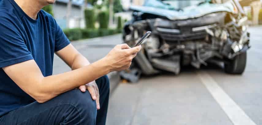 man using cell phone near car accident