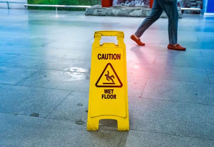 man walking past caution wet floor sign