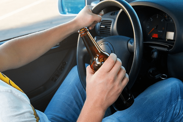 Person holding a beer bottle while driving