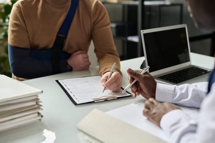 legal professional discussing paperwork with person with injured arm