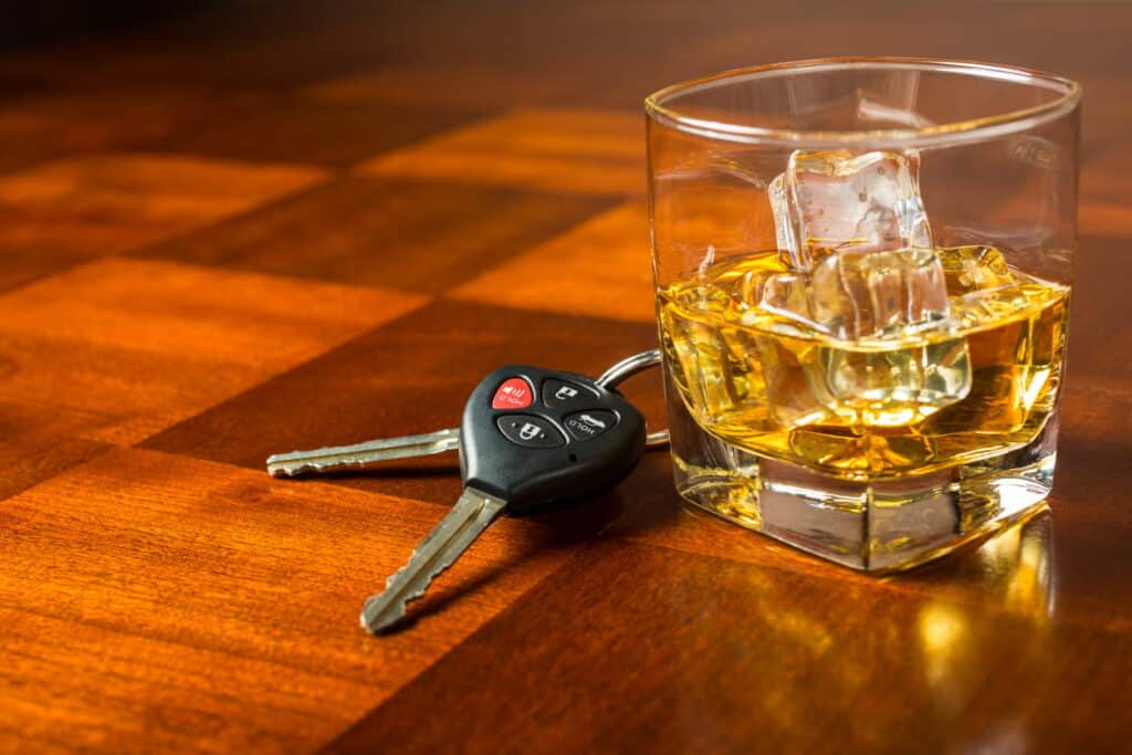 Drunk driving explained, a pair of keys sits next to an alcoholic beverage on a bar countertop.