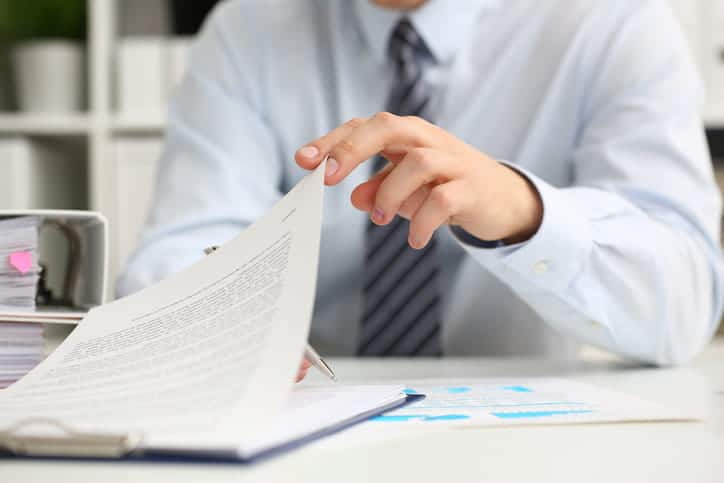 Focus is on a Miami car accident attorney as he works at his desk, filling out paperwork.