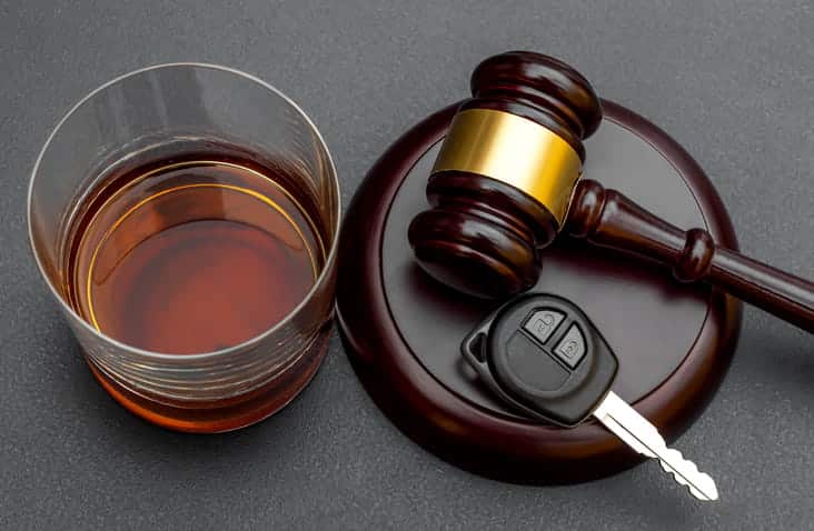 An alcoholic drink next to a gavel from a Miami drunk driver crash lawyer A pair of keys rests on the gavel.