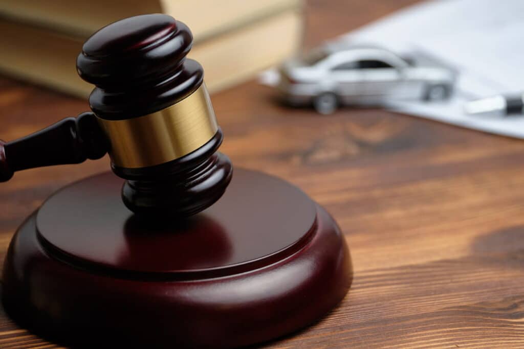 A closeup of a gavel sitting on a Miami, Florida car accident attorney's desk. In the background blurred out is a toy car next to a stack of books.