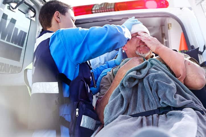 A medic treating a man after he received car accident injuries.