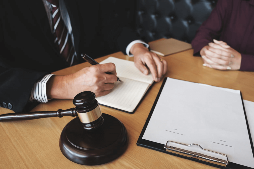 Focus is on a hit-and-run accident attorney working with their client. On their desk is paperwork and a gavel.