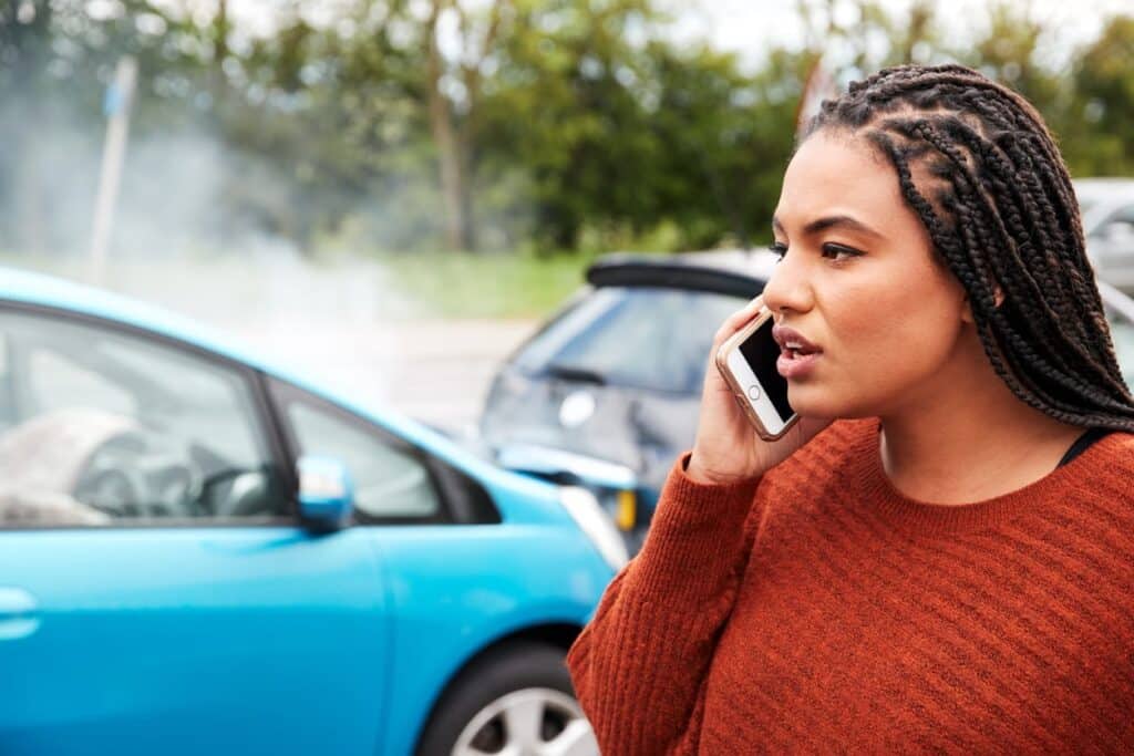 A woman on her phone calling for help after crashing her leased vehicle.