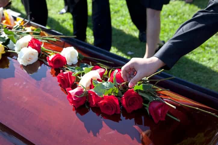 Person putting flowers on a casket at a funeral
