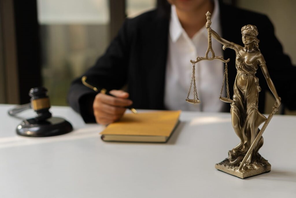 A Miami personal injury lawyer sits at their desk with a book in front of them. Next to them is a Lady Justice statue and a gavel.