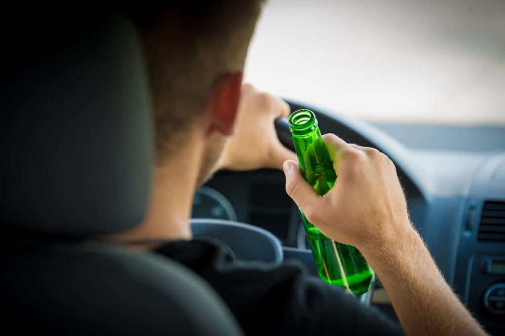 Man holding an open beer bottle while driving