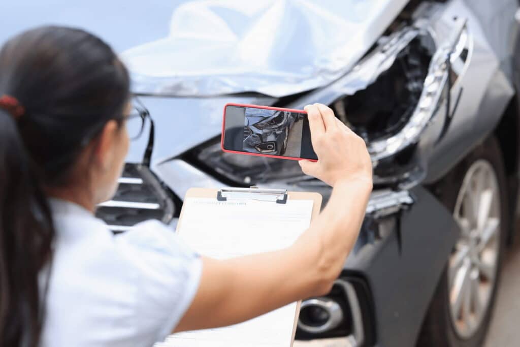 A woman taking a photo of a car accident
