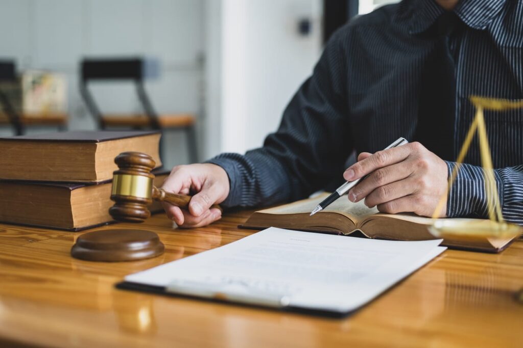 A medical malpractice lawyer using a gavel at his desk. In front of him is paperwork and a stack of books.