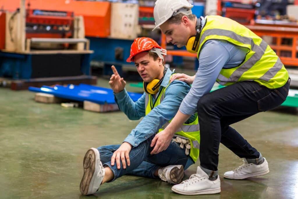 Worker on the ground injured getting help from another employee