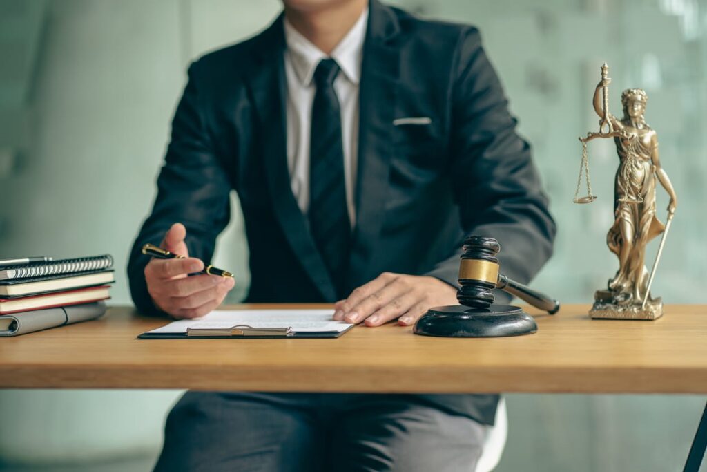 A Miami Uber accident lawyer working on paperwork at his desk. Next to him is a gavel and the scales of justice. 