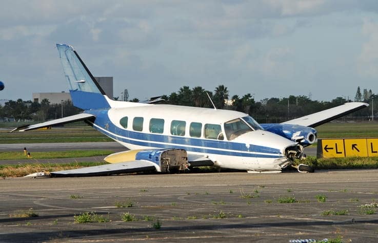 An damaged airplane sitting the wrong way on a runway after an accident
