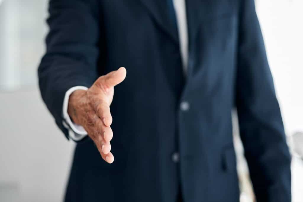 A rideshare accident lawyer has his hand outstretched in greeting.