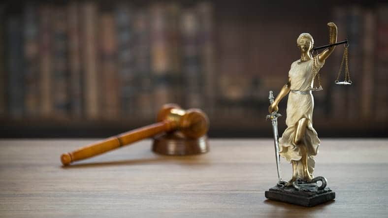A Lady Justice statue and a gavel on a car accident attorney's desk.
