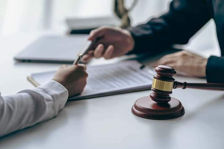 A car accident attorney reviewing paperwork with their client. Next to them is a gavel. 