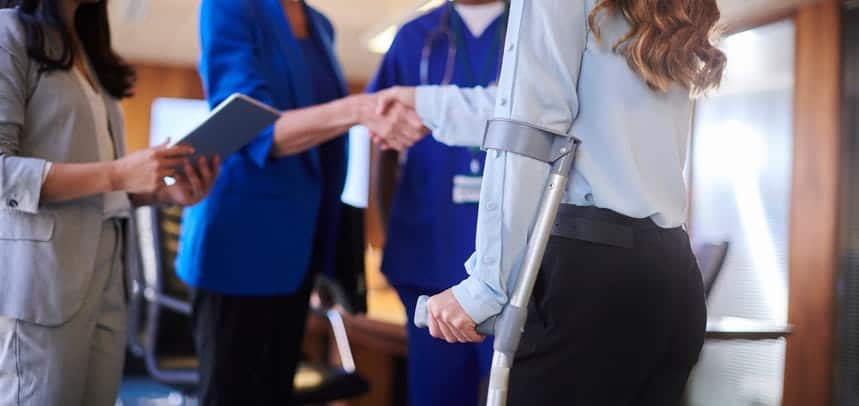 A woman on crutches meeting with a doctor and personal injury lawyer