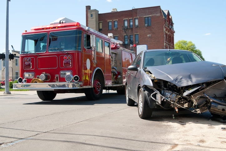 A car accident scene with a firetruck next to a smashed car