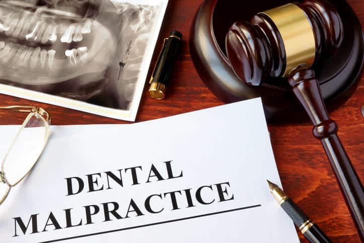 A document that reads: dental malpractice next to a X-ray of teeth, a gavel, and a pen.