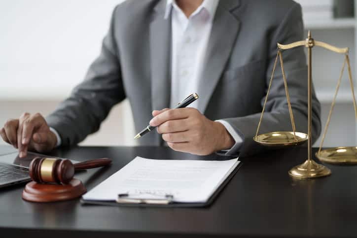 A dental malpractice lawyer working on paperwork at his desk. In front of him is a gavel and the scales of justice. 