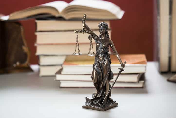 A Lady Justice statue in front of a stack of books.