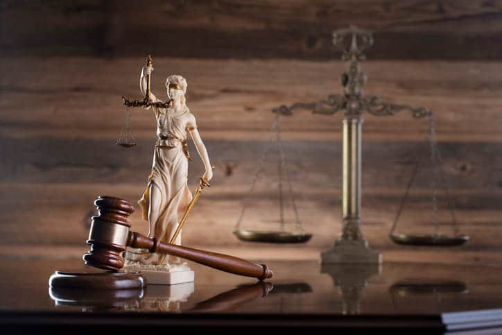 A gavel, a Lady Justice statue and the scales of justice on an attorney's desk. 