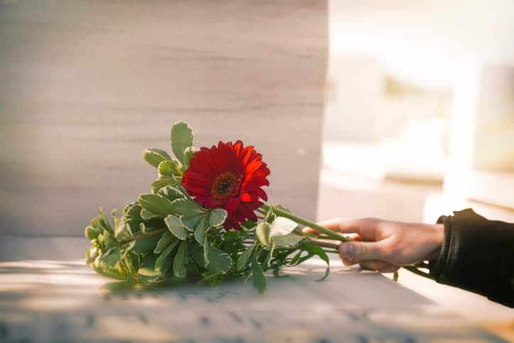 A person setting flowers down at a memorial. 