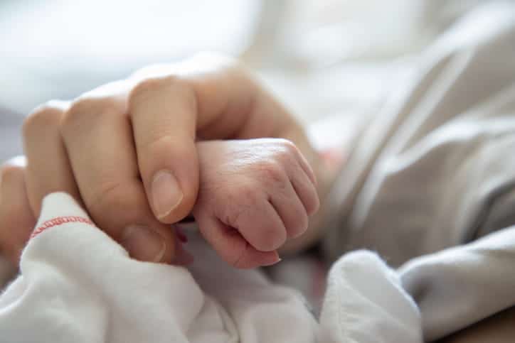 A parent holding their newborns hand. 