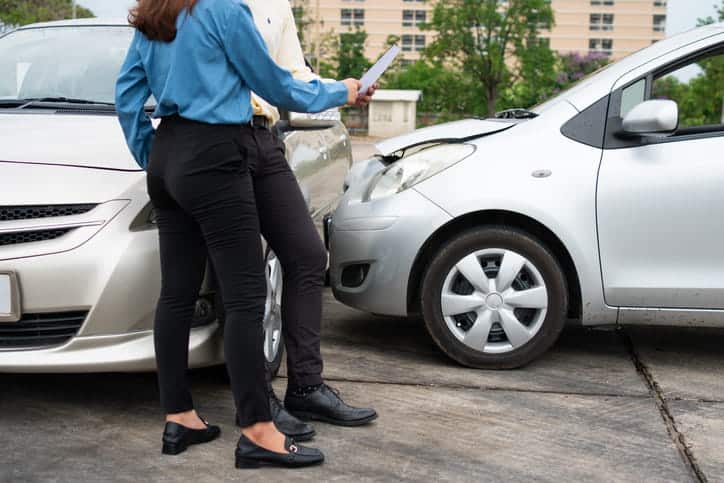 Two people exchange information after a car accident. 