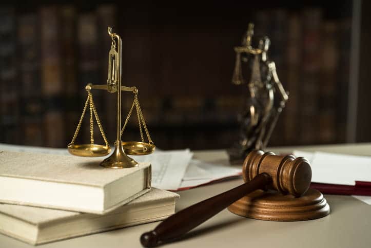 The scales of justice on a stack of books, the Lady Justice statue and a gavel on a car accident injury attorney's desk. 