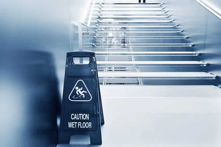 A caution wet floor sign in front of a staircase to prevent slip and falls