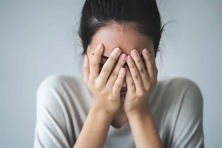 A woman holding her face during emotional distress. 