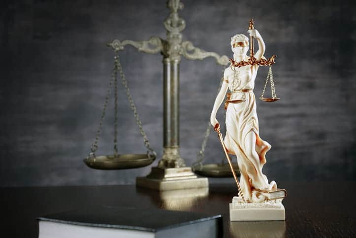 A Lady Justice statue in front of the scales of justice on a personal injury attorney's desk. 