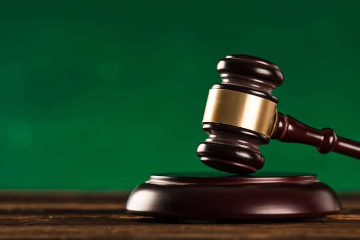 A Wooden Gavel Positioned On A Desk In Front Of A Textured Green Wall, Representing Legal Authority In A Car Accident Attorney's Office.
