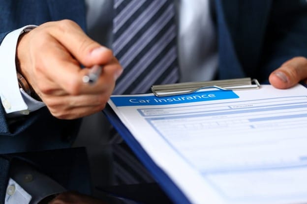Is A Car Accident Insurance Settlement Taxable? 1 A Person In A Suit Holding A Clipboard Labeled &Quot;Car Insurance,&Quot; Preparing To Fill Out A Form Related To A Car Accident Insurance Claim.