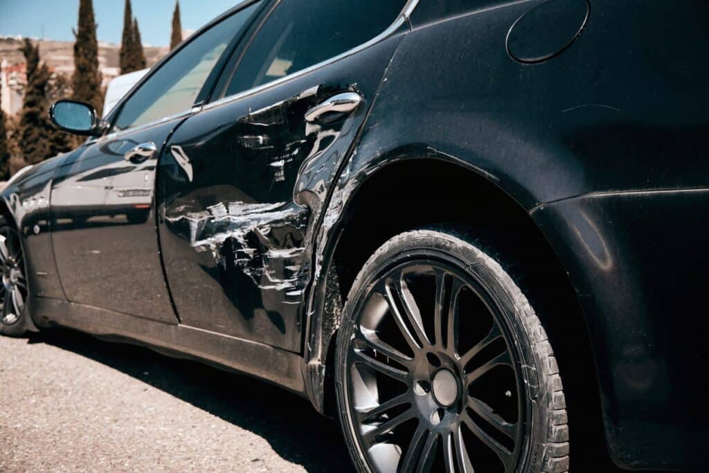 Average Settlement For Non-Injury Car Accidents 62 Close-Up Of A Black Car With Visible Side Damage And Scratches After A Collision.